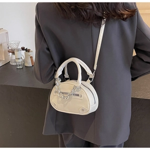 Détail du petit sac blanc avec chaîne argentée porté sur une veste de blazer grise