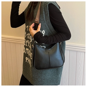 Detail of a black crossbody bucket bag with a wide vintage geometric pattern strap