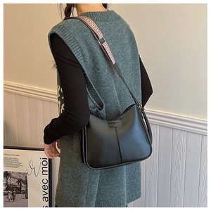 Détail du sac de selle noir avec bandoulière large tissée à motifs géométriques