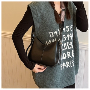 Détail d'un sac seau noir en cuir PU avec bandoulière géométrique et surpiqûres