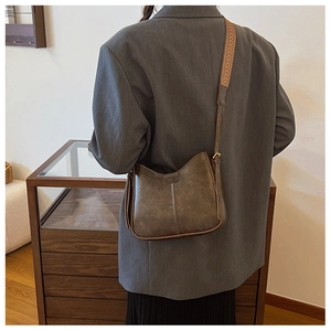 Detail of vintage brown half-moon crossbody bag with patterned wide shoulder strap