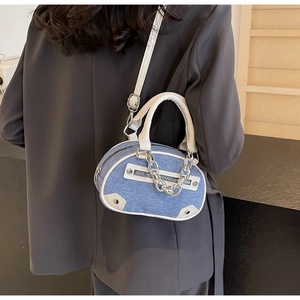 Sac bandoulière en denim bleu et cuir blanc porté par un mannequin dans un cadre moderne