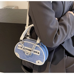 Détail du mini sac en denim bleu avec chaîne argentée et garniture en cuir blanc sur noir