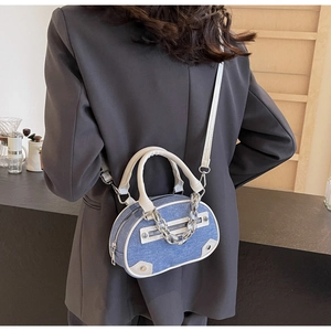 Detail of blue denim patchwork handbag with white leather trim and silver chain strap