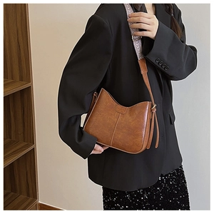 Close-up of brown vintage bucket bag featuring a stylish patterned woven wide shoulder strap