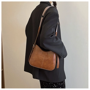 Brown vintage underarm bag with ethnic style woven strap shown on a model