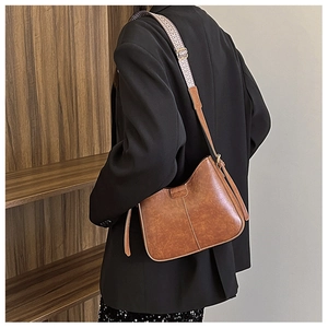 Détail d'un sac seau vintage en cuir marron avec bandoulière tissée aux motifs colorés