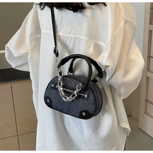 Détail du sac bandoulière en denim gris avec chaîne argentée et finitions en cuir noir
