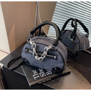 Détail du mini sac en denim bleu avec poignée en cuir noir et chaîne argentée
