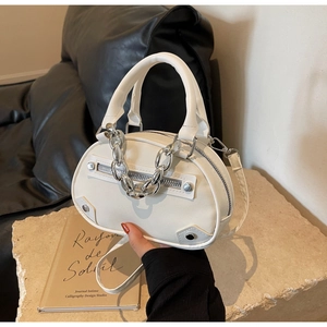 Détail du sac ovale en cuir blanc avec chaîne métallique argentée et rivets décoratifs