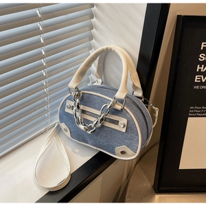 Détail du sac en denim bleu avec bordure en cuir blanc et grosse chaîne argentée