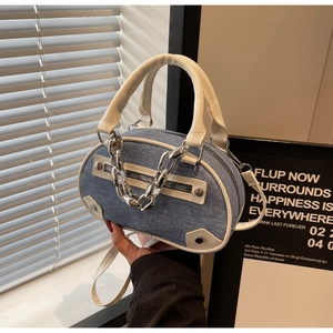Détail du sac ovale en denim avec bordure en cuir blanc et chaîne argentée