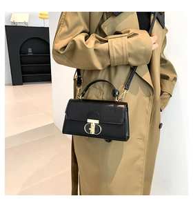Dettaglio di una borsa a tracolla nera minimalista con chiusura a doppio anello dorata