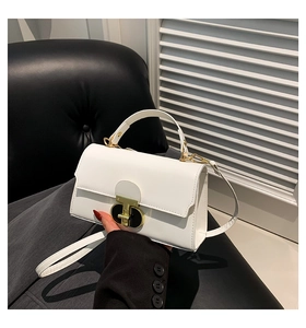 Close-up of white leather crossbody bag featuring distinctive gold geometric metal buckle