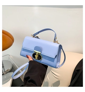 Detail of light blue crossbody square bag with a golden metal twist lock and smooth texture