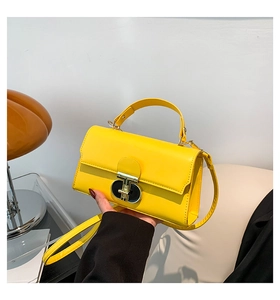 Close-up of bright yellow crossbody bag with metal twist lock and sleek top handle
