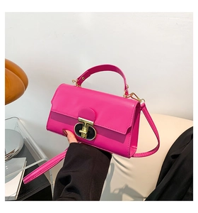 Close-up of bright pink crossbody bag showing gold lock buckle and glossy leather texture