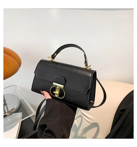 Detail of black matte leather handbag featuring unique gold buckle and adjustable strap