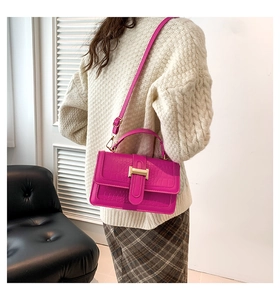 Detail of rose red crocodile pattern PU leather handbag with gold metal clasp and long strap