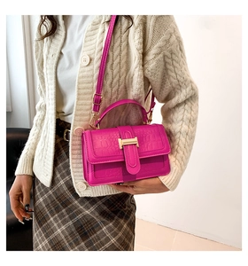 Detail view of fuchsia crocodile pattern leather bag with golden H-shaped buckle