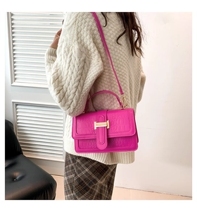 Detailed side view of pink crocodile pattern handbag with gold H buckle and slim strap