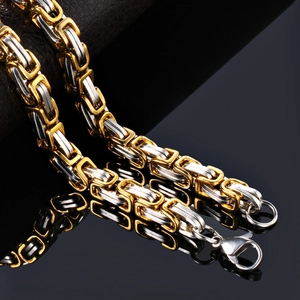 Two-tone Byzantine titanium steel bracelet with lobster clasp on reflective black surface