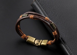 Gros plan d'un bracelet en cuir tressé marron avec fermoir en bronze vintage et spirales