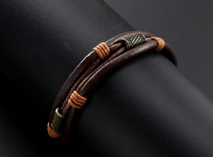 Détail d'un bracelet vintage multicouche en cuir avec perles de bronze et cordage