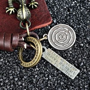 Vintage leather keychain with bronze lizard charm and engraved quote tag on dark stones