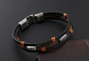 Détail du bracelet multicouche en cuir avec gravures métalliques et fermoir rétro