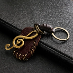 Macro shot of vintage bronze treble clef charm on dark brown leather keychain strap