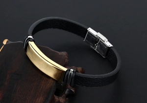 Détail d'un bracelet en cuir pour homme avec plaque en métal brossé doré et fermoir acier