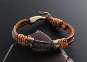 Nahaufnahme von geflochtenem Lederarmband mit bronzenem Legierungshaken auf dunklem Holz