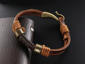 Detail eines Vintage-Lederarmbands mit bronzefarbenem Fischhaken-Verschluss und geschnitzten Perlen