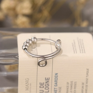 Macro shot of silver stress relief ring with four rotating beads on a vintage background