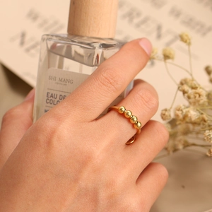 Detail of adjustable gold ring with four rotating beads for anxiety relief shown on hand