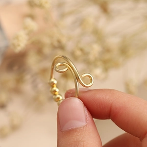 Detailed view of gold wave anxiety ring with sliding beads for stress relief