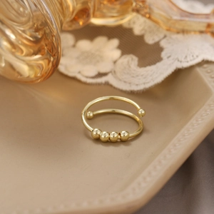 Detail of adjustable gold spinner ring with sliding beads for anxiety relief on elegant tray