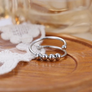 Macro view of silver spiral anti-anxiety ring with four movable beads on wood and lace