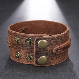 Retro vintage brown leather wide wrap bracelet with bronze metal buckles on dark background
