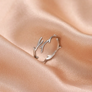 Detailed close-up of a silver branch-shaped adjustable ring on a soft silk background