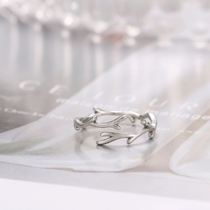 Close-up of minimalist silver branch ring with realistic wood texture on magazine