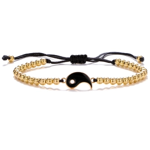 Detailed macro of woven Tai Chi Yin Yang bracelet with gold beads and black cord