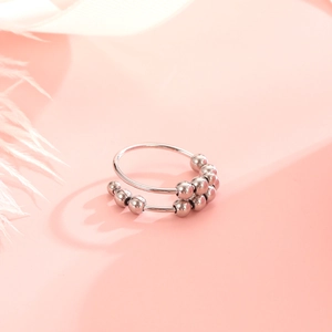Fidget anxiety ring with silver beads and double band design on soft background