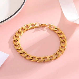 Detailed macro of gold Cuban link bracelet featuring textured grid pattern on the metal