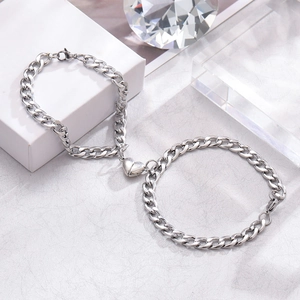 Polished silver magnetic heart Cuban link couple bracelets on minimalist background