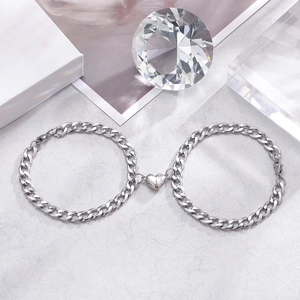 Polished silver magnetic heart Cuban chain bracelets for couples on elegant gift stand