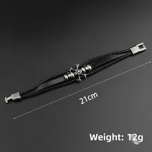 Detailansicht eines silbernen Totenkopf-Charms auf geflochtenem schwarzen Lederarmband