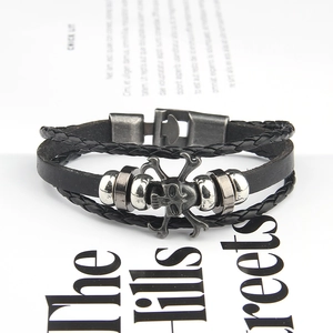Detail eines mehrlagigen schwarzen Lederarmbands mit Vintage-Totenkopf und Metallperlen