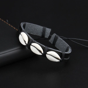 Detail view of woven leather bracelet with three natural white cowrie shells